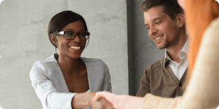 A smiling woman shakes hands with a colleague